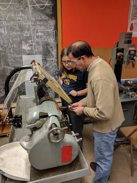 A mentor showing a student how to use the lathe
